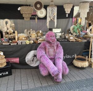 Stall met handgemaakte decoraties en accessoires, inclusief manden, kralen en een opvallende roze gorilla pop, bij een marktstand voor evenementen en markten 2026.